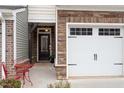 Townhome's front entry with a covered porch, red chairs, and a dark door at 505 Great Eno Path, Hillsborough, NC 27278
