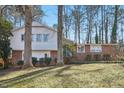 View of home's exterior with mature trees on a sunny day; home features white and brick at 5410 Thayer Dr, Raleigh, NC 27612