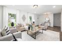 Bright living room featuring neutral furniture, large windows, and wood flooring at 106 N Trail Dr, Raleigh, NC 27615