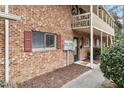 A close up view of a brick townhouse with a covered balcony and manicured landscaping at 130 S Estes Dr # G3, Chapel Hill, NC 27514