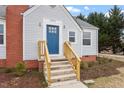 Close-up of a charming house featuring a blue door, brick chimney, and well-maintained landscaping at 2001 Rolesville Rd, Wake Forest, NC 27587