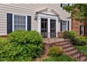 Close-up of the entryway with black double doors and sidelights, brick steps, and lush landscaping at 3929 Browning Pl, Raleigh, NC 27609