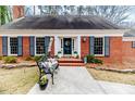 Charming red brick home with blue shutters, a manicured lawn, and a welcoming front porch at 612 W Chisholm St, Sanford, NC 27330