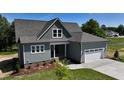 Beautiful two-story home with a gray roof, attached garage, manicured lawn, and lush landscaping at 83 Nottoway Lane, Wendell, NC 27591