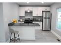 Well-lit kitchen with white cabinets, gray countertops, stainless steel refrigerator, and a breakfast bar at 1210 Shaw St, Burlington, NC 27217