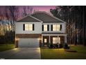 Exterior view of a charming two-story home at dusk, featuring stone accents and a well-lit front yard at 172 Great Gln, Rocky Mount, NC 27804