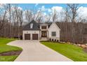 Inviting two-story house boasts a stone and white exterior, accented by a long driveway and lush green lawn at 227 Beech Slope Ct, Chapel Hill, NC 27517