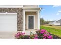 Close-up of townhome entry with stone accents, gray door, and landscaped flowers at 268 Moyer Dr, Graham, NC 27253