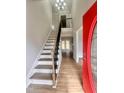 Bright foyer featuring wood floors, stairs with a black metal railing, and a red front door at 3 Azzi Ct, Durham, NC 27703