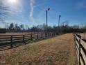 Horse facilities with an outdoor riding ring and surrounding grass pasture on a clear day at 7027 Old 421 Rd, Liberty, NC 27298