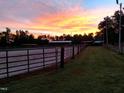 Horse facilities with outdoor riding ring surrounded by green pasture under a stunning sunset at 7027 Old 421 Rd, Liberty, NC 27298