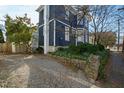 View of a blue house features stone walls, lush greenery, and a gravel driveway at 101 S Bloodworth St, Raleigh, NC 27601