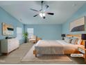 Beautiful staged bedroom with light blue walls, a ceiling fan, and neutral toned furniture at 151 N Great White Way, Clayton, NC 27527