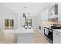 Modern kitchen featuring white cabinets, stainless steel appliances, a spacious island with a sink, and sleek pendant lights at 605 Shawnee Dr, Louisburg, NC 27549