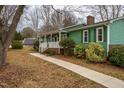 Charming green home featuring a welcoming front porch and lush, landscaped surroundings at 623 Rolling Rd, Haw River, NC 27258
