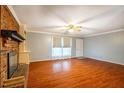 Spacious living room featuring gleaming hardwood floors and a cozy brick fireplace at 623 Rolling Rd, Haw River, NC 27258