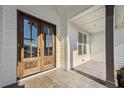 Close-up of the wooden front door with glass panes and a covered porch, adding a touch of elegance at 654 Christian Light Rd, Fuquay Varina, NC 27526