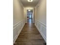 Well-lit hallway with elegant wall paneling, hardwood floors, and a view to the living room at 19 Oriental St, Angier, NC 27501