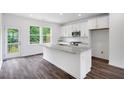 Bright kitchen with white cabinets, stainless appliances, granite countertops and dark laminate flooring at 427 Rowe Way, Knightdale, NC 27545
