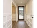 Bright and welcoming entryway with wood floors, white wainscoting, and a glass-paneled front door at 428 Hampshire Ct, Four Oaks, NC 27524
