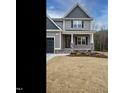 A lovely house with a covered front porch, gray siding, and stylish black garage door at 428 Hampshire Ct, Four Oaks, NC 27524