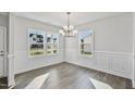 Bright dining room featuring hardwood floors, white trim, a modern chandelier, and large windows at 617 Spellbrook Rd, Zebulon, NC 27597