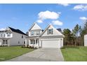 New home featuring a well-manicured lawn, light gray siding, black shutters, and a two car garage at 617 Spellbrook Rd, Zebulon, NC 27597