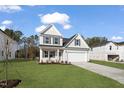 New home featuring a well-manicured lawn, light gray siding, black shutters, and a two car garage at 617 Spellbrook Rd, Zebulon, NC 27597