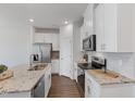 Bright kitchen showcases white cabinetry, stainless steel appliances, granite countertops, and hardwood flooring at 907 Field Ivy Dr, Fuquay Varina, NC 27526