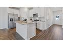 Modern kitchen featuring white cabinetry, stainless steel appliances, granite countertops, and hardwood flooring at 907 Field Ivy Dr, Fuquay Varina, NC 27526
