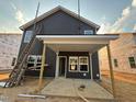 New construction home with gray siding, white trim, covered patio, and ladder propped up against the side at 97 Willow Cameron Way, Angier, NC 27501