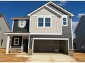 Two-story home with a mix of board and batten and lap siding, a stone base and an attached two-car garage at 97 Willow Cameron Way, Angier, NC 27501