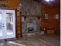 Cozy living room featuring a stone fireplace and wood-paneled walls and new flooring at 105 Lake Rd, Henderson, NC 27537