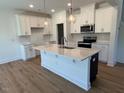 Bright, spacious kitchen featuring a large center island, stainless appliances, and pendant lighting at 106 Little Creek Dr, Lillington, NC 27546