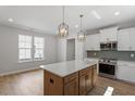 Modern kitchen featuring stainless appliances, stylish lighting, and a large island, seamlessly flowing into the living area at 272 White Oak Garden Way # 209, Garner, NC 27529
