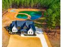 Magnificent aerial view of an estate home with a private pond, showcasing lush landscaping, and a long, winding driveway at 299 Seaforth Landing Dr, Pittsboro, NC 27312
