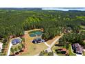 Breathtaking aerial view of an estate home, lush forest, private pond, and pristine landscaping at 299 Seaforth Landing Dr, Pittsboro, NC 27312