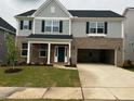 Two-story home featuring a brick and gray siding exterior, black shutters, and a two-car garage at 322 Oak Branch Trl, Garner, NC 27529