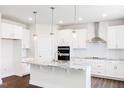 Bright, open kitchen with white cabinets, granite countertops, stainless steel appliances, and a large center island at 456 Barbour Farm Ln, Four Oaks, NC 27524