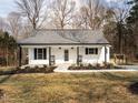 Inviting single-story home with a classic white facade, rocking chairs on the porch, and neatly landscaped front yard at 4664 Quarter Creek Ln, Liberty, NC 27298