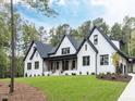 Elegant white brick exterior featuring sleek black trim, gabled roofs, and a lush green lawn at 49 Clear Springs Ct, Pittsboro, NC 27312