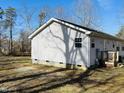 A view of the side of a single-story home with light siding and a small deck at 610 Apple St, Gibsonville, NC 27249