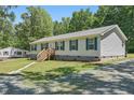Well-maintained single-story home with teal shutters, complemented by a neatly landscaped yard and gravel driveway at 610 Apple St, Gibsonville, NC 27249