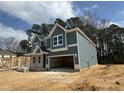 View of the home showcasing its gray siding, architectural details, and the surrounding natural landscape at 744 Portland Rose Dr, Knightdale, NC 27545
