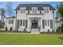 Stunning two-story white home featuring a manicured lawn, complementary landscaping, and black trim at 7723 Roberts Rd, Apex, NC 27523