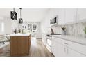 Bright modern kitchen featuring white cabinets, stainless steel appliances, island with seating, and open to the living area at 913 Myers Point Dr, Morrisville, NC 27560