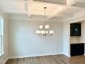 Dining room features a coffered ceiling, stylish chandelier, and a dark bar with a tile backsplash at 62 Blue Iris Pkwy # 125, Clayton, NC 27520
