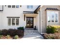 Close-up of the home's entryway showcasing a wooden front door and stone steps surrounded by manicured landscaping at 7212 Summer Tanager Trl, Raleigh, NC 27614