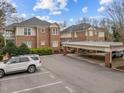 View of the brick condo building with a covered parking area and parking lot at 100 Edenburgh Rd # 202, Raleigh, NC 27608