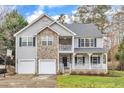 Beautiful two-story home featuring stone accents, a two-car garage, and a charming front porch and second story balcony at 1079 Vauxhall Dr, Apex, NC 27502